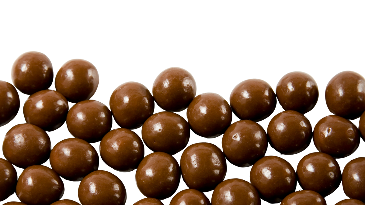 A close-up of glossy brown chocolate-covered round candies arranged in a curved row against a plain white background.