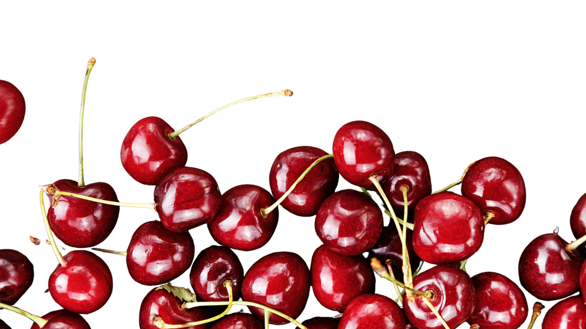 A pile of glossy red cherries with green stems scattered across a plain white background.