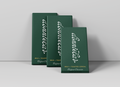 Three dark green rectangular boxes of 'dunnbear' Milk + Toasted Cereal Belgian Chocolate arranged in a staggered studio composition against a light gray background.